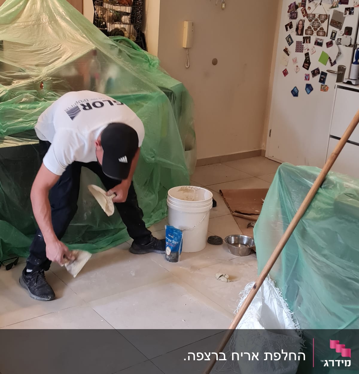 אדם משפץ רצפה עם דלי, מטאטא ושק מלט